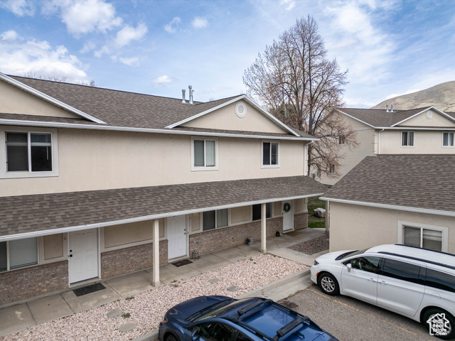 420 West 2000 South, Unit 8 Perry, UT 84302 - Photo 1 of 1 Multi unit property featuring a porch, a shingled roof, and stucco siding with garage and parking
