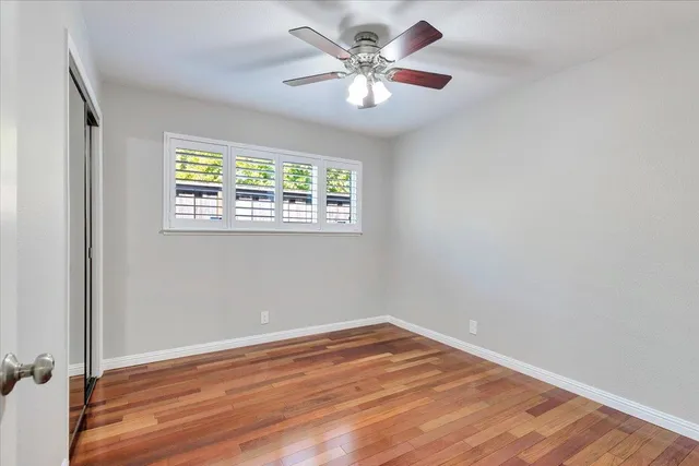 a view of a room with wooden floor and a ceiling fan