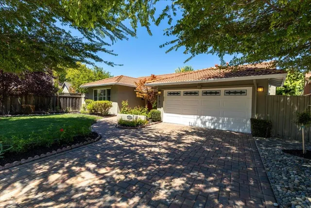 a front view of a house with a garden and trees