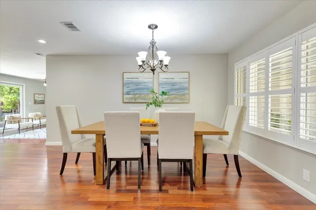 a dining room with furniture a chandelier and wooden floor