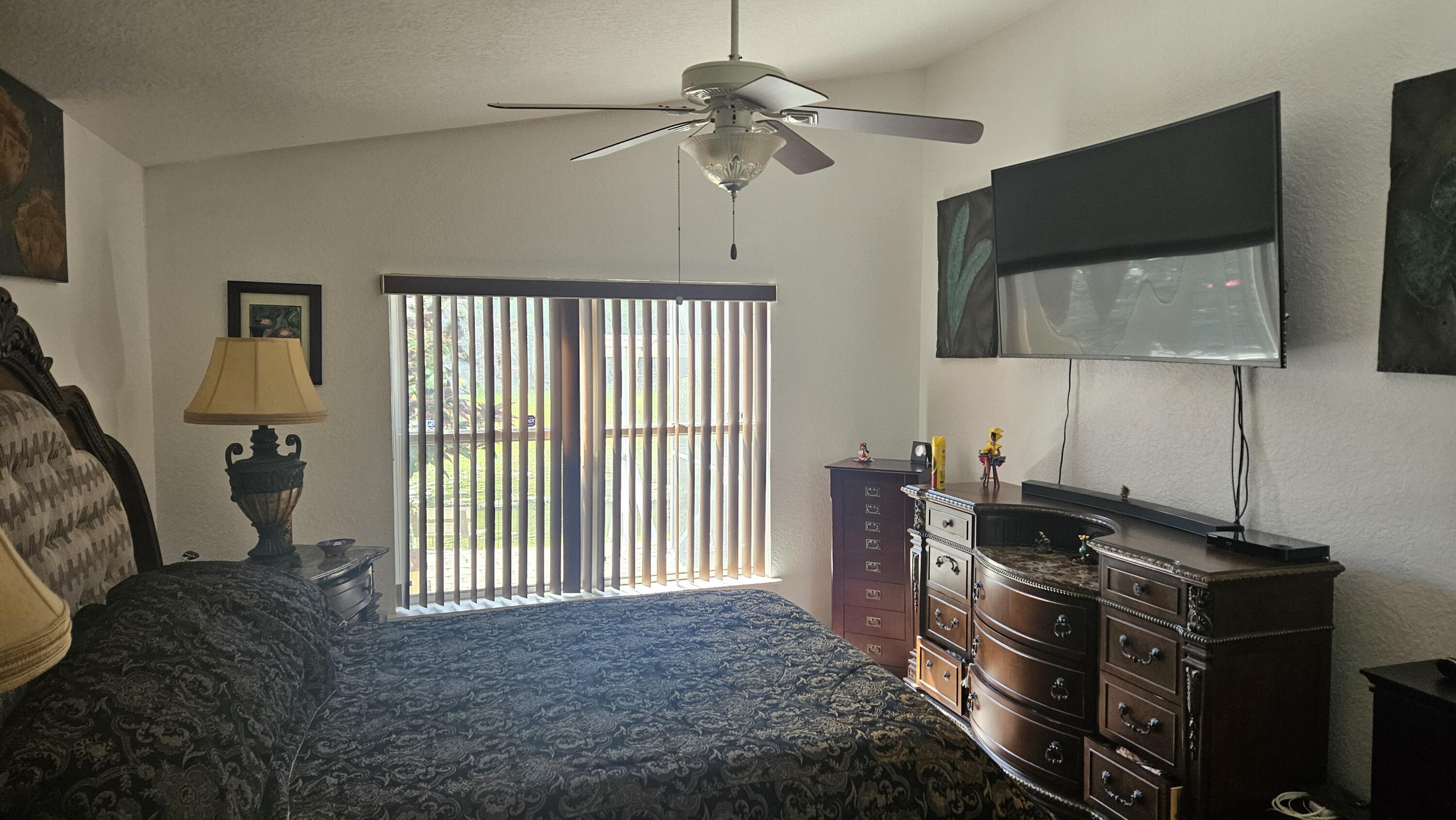 1768 Sawgrass Circle Greenacres, FL 33413 - Photo 23 of 40 a bedroom with a bed and a flat tv screen on the dresser