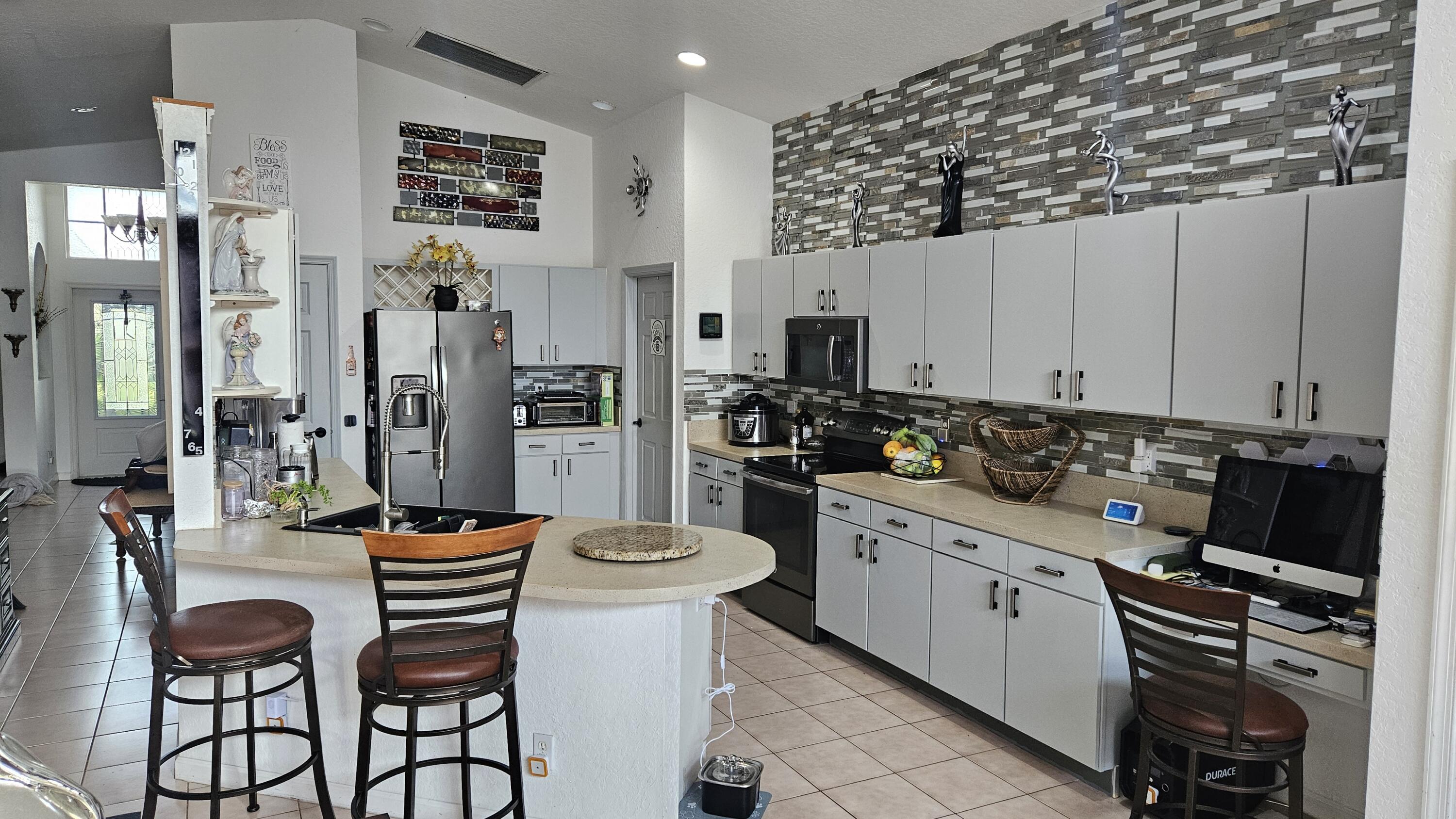 1768 Sawgrass Circle Greenacres, FL 33413 - Photo 31 of 40 a kitchen with stainless steel appliances a refrigerator and a stove top oven