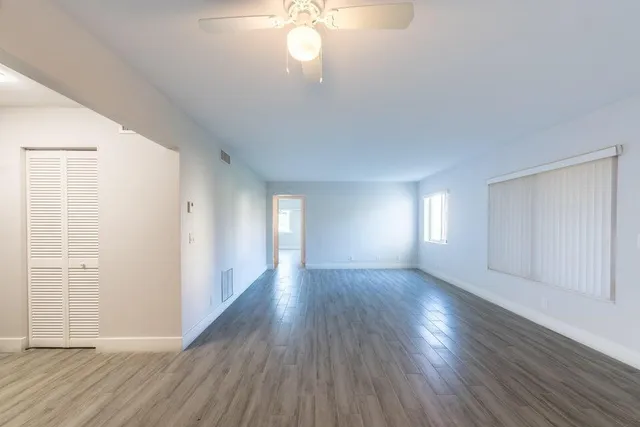 an empty room with wooden floor and windows