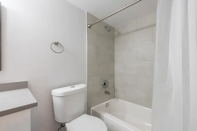 a white toilet sitting next to a bath tub