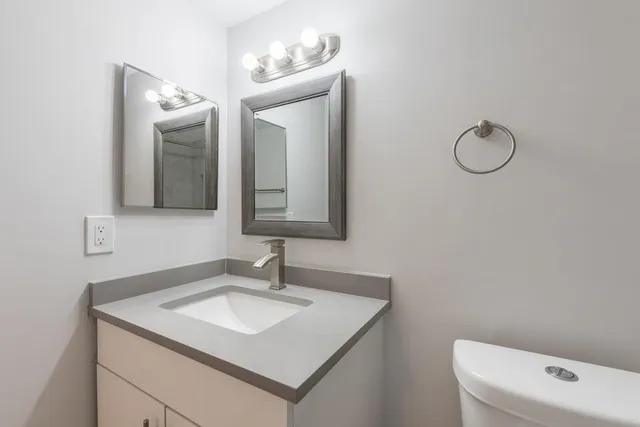 a bathroom with a toilet sink vanity and mirror