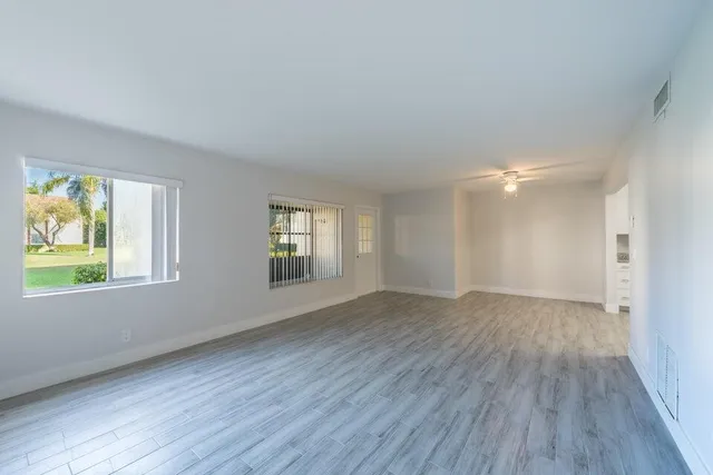 a view of an empty room with wooden floor and a window