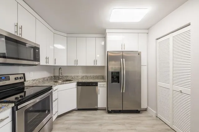 a kitchen with stainless steel appliances granite countertop a stove a refrigerator and a microwave