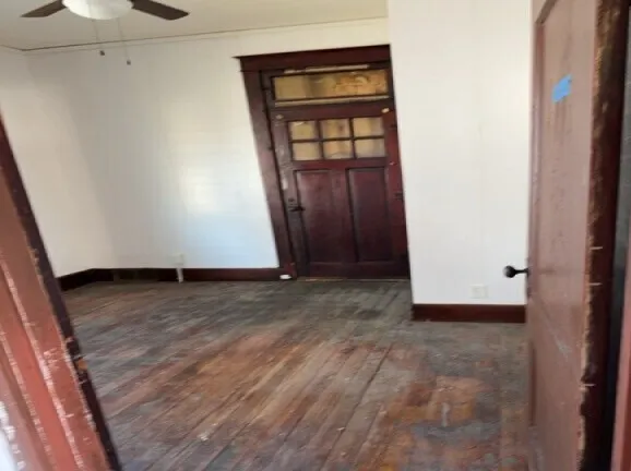 a view of an empty room with wooden floor and cabinets