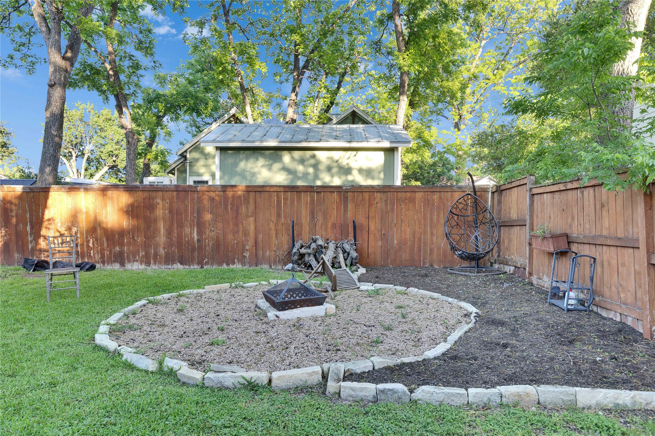 4607 Evans Avenue, Unit B Austin, TX 78751 - Photo 32 of 34 Backyard featuring a circular landscape bed with stone edging, a separate mulched area, and a wood privacy fence