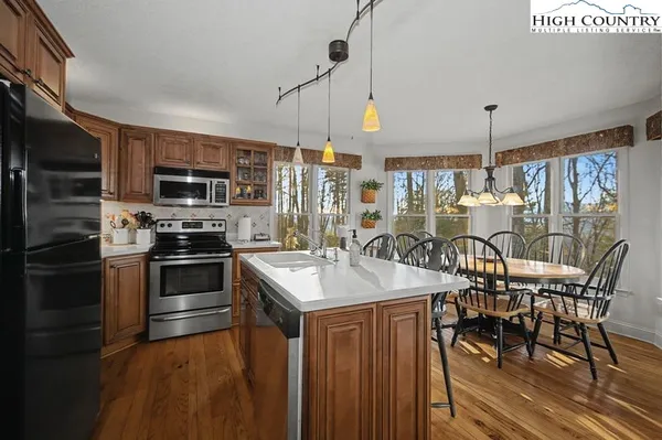 a kitchen with stainless steel appliances granite countertop a stove top oven a sink dishwasher a dining table and chairs with wooden floor