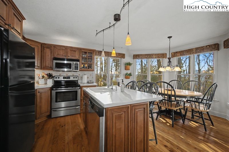 137 Granny's Ridge Road Ferguson, NC 28624 - Photo 10 of 27 a kitchen with stainless steel appliances granite countertop a stove top oven a sink dishwasher a dining table and chairs with wooden floor
