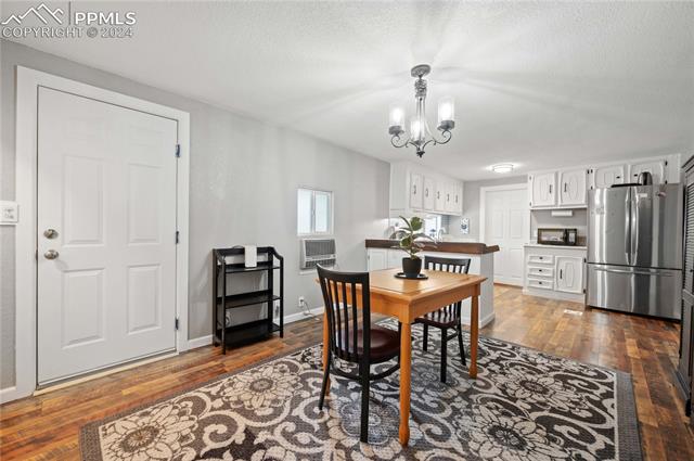 1326 Forest Road Colorado Springs, CO 80906 - Photo 6 of 22 Dining space with a textured ceiling, an inviting chandelier, and dark hardwood / wood-style flooring