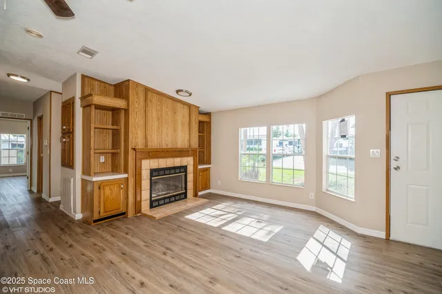 a view of an empty room with window and fire place