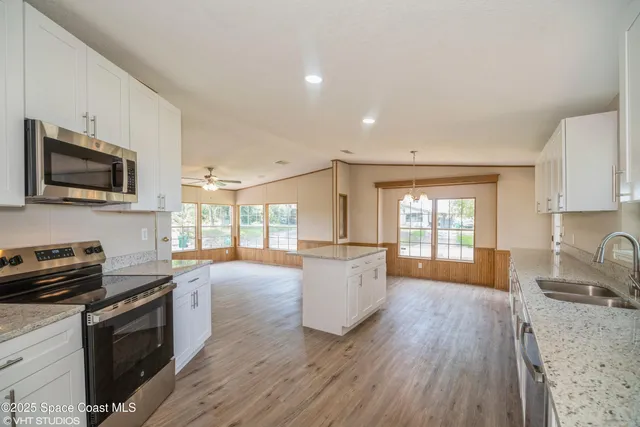 a kitchen with granite countertop a stove top oven a sink dishwasher a dining table and chairs with wooden floor