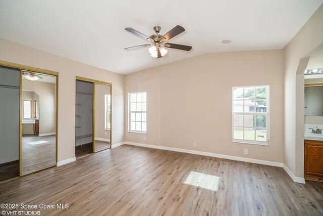 a view of an empty room with window and wooden floor