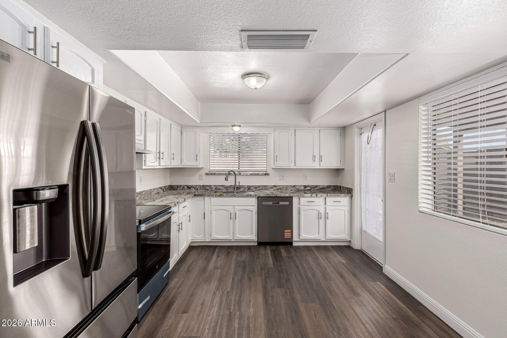 2540 West Roveen Avenue Phoenix, AZ 85029 - Photo 13 of 31 a kitchen with stainless steel appliances granite countertop a refrigerator a sink dishwasher a stove and white countertops with wooden floor