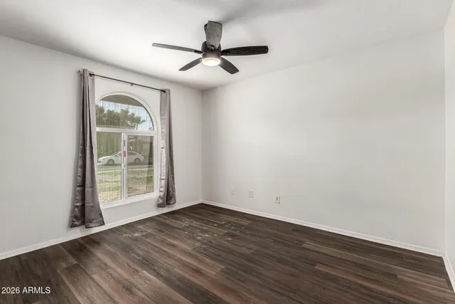 an empty room with wooden floor fan and windows