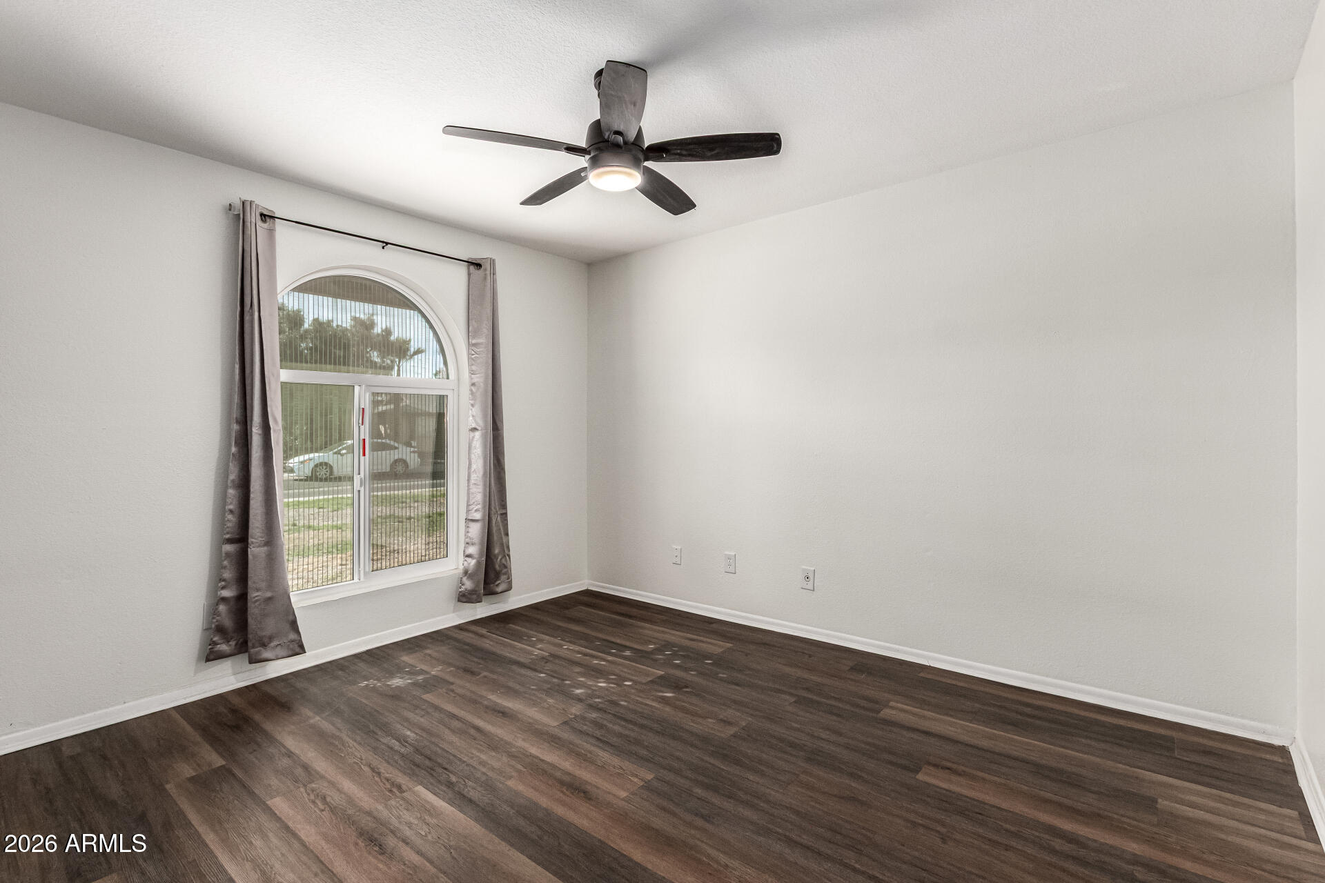 2540 West Roveen Avenue Phoenix, AZ 85029 - Photo 23 of 31 an empty room with wooden floor fan and windows