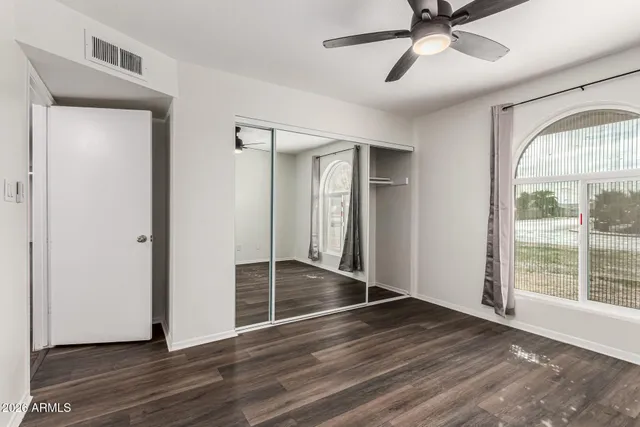 a view of empty room with wooden floor and fan