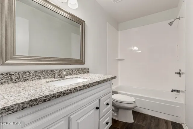 a bathroom with a granite countertop sink a toilet and a bathtub