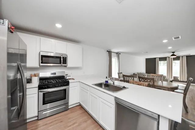 a kitchen with stainless steel appliances a sink a stove a microwave a refrigerator and cabinets