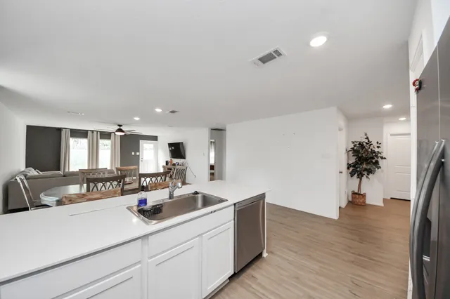 a view of a kitchen with kitchen island a sink wooden floor and a potted plant