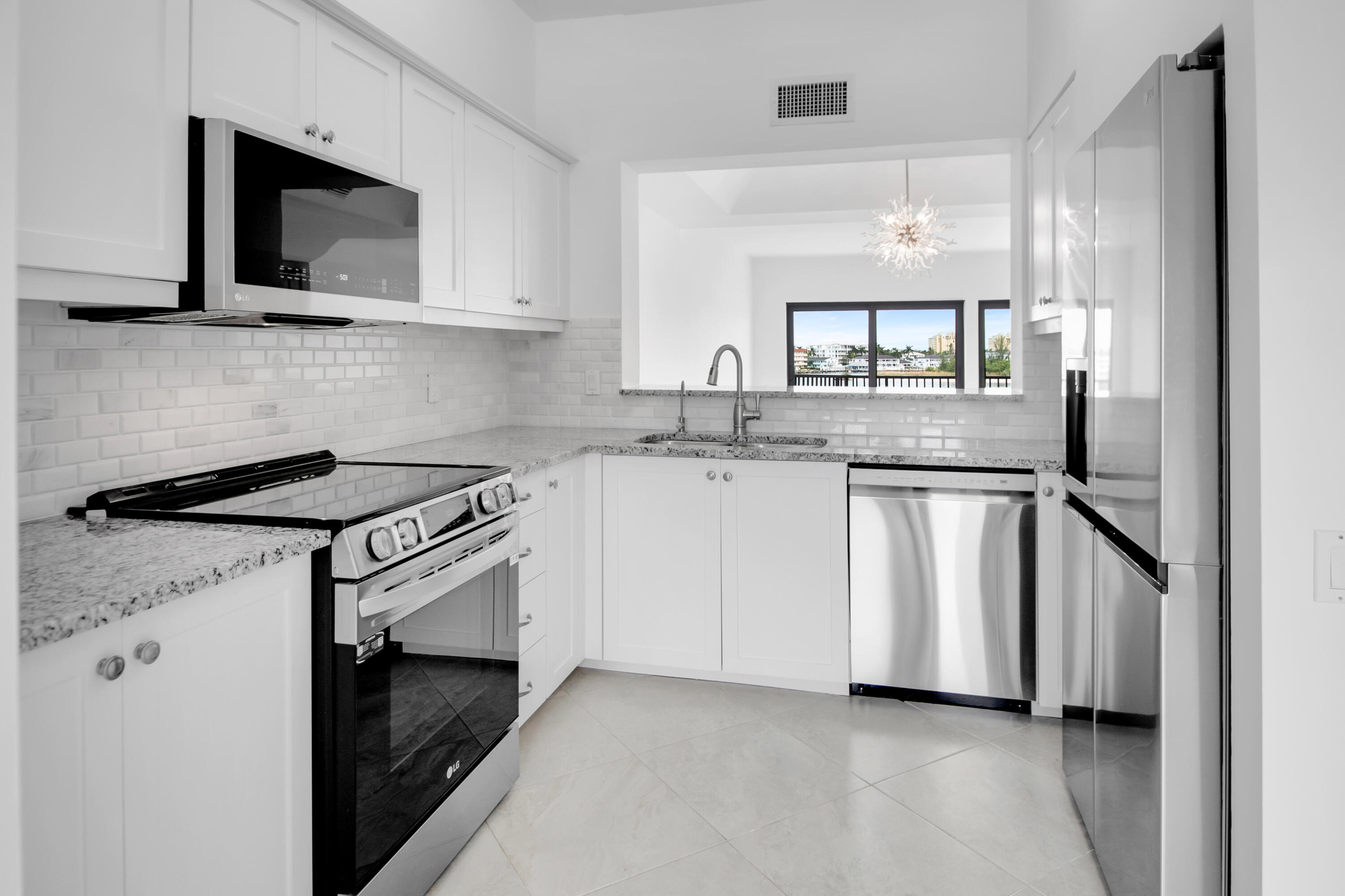 231 La Peninsula Boulevard, Unit 231 Naples, FL 34113 - Photo 11 of 42 a kitchen with white cabinets and white appliances