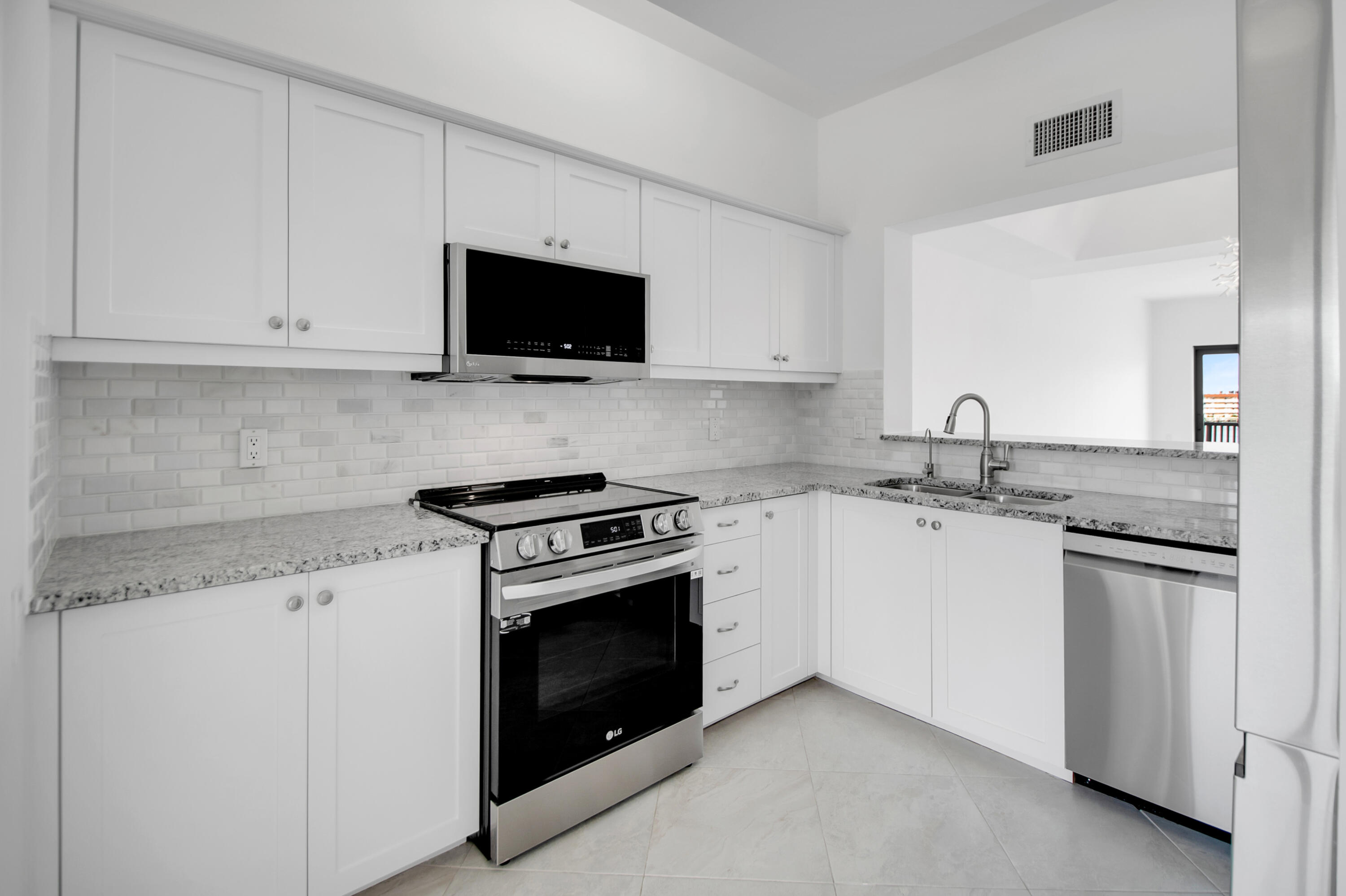 231 La Peninsula Boulevard, Unit 231 Naples, FL 34113 - Photo 12 of 42 a kitchen with granite countertop white cabinets and stainless steel appliances