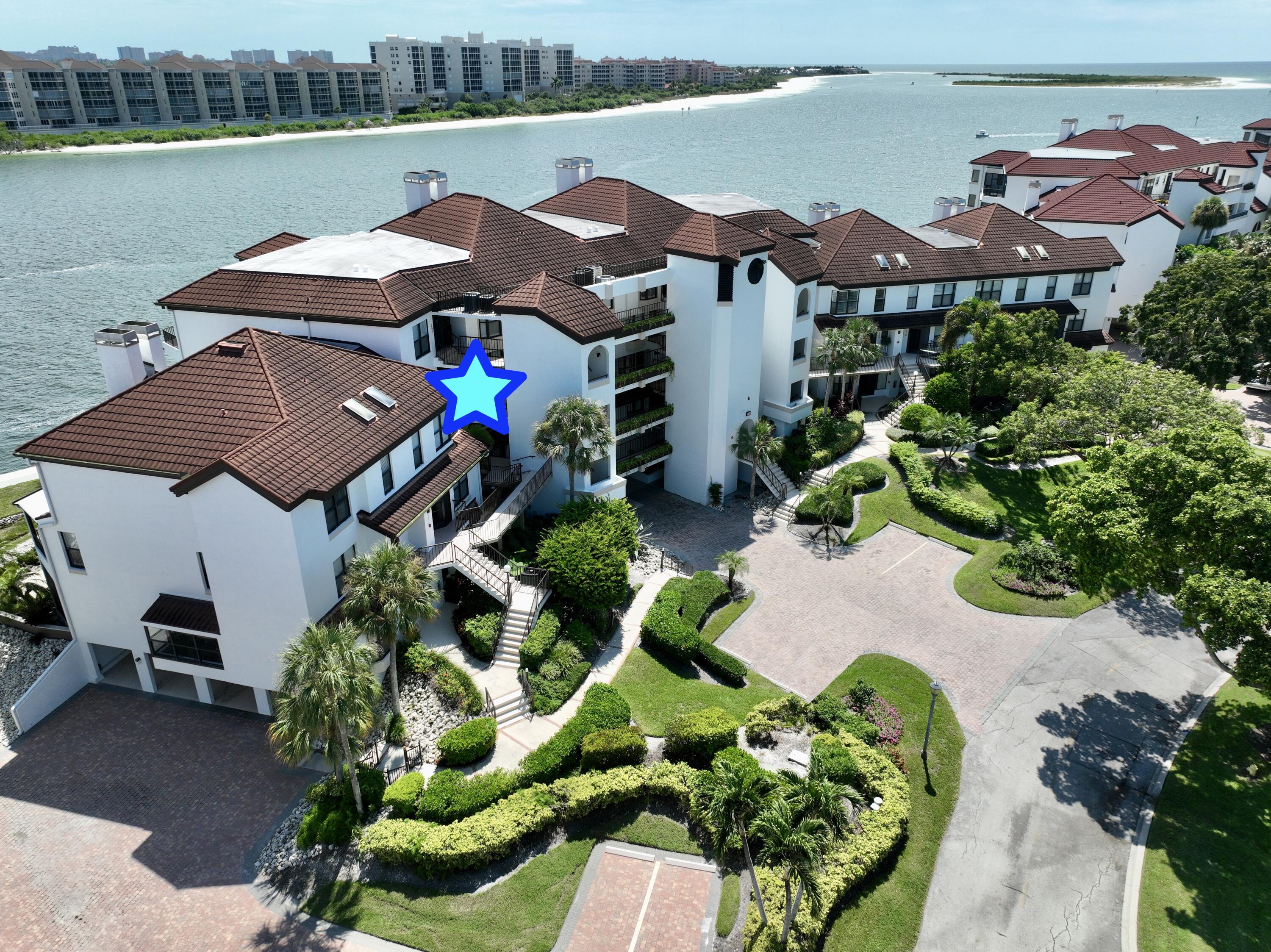 231 La Peninsula Boulevard, Unit 231 Naples, FL 34113 - Photo 32 of 42 a view of a house with a yard and a lawn chair under an umbrella