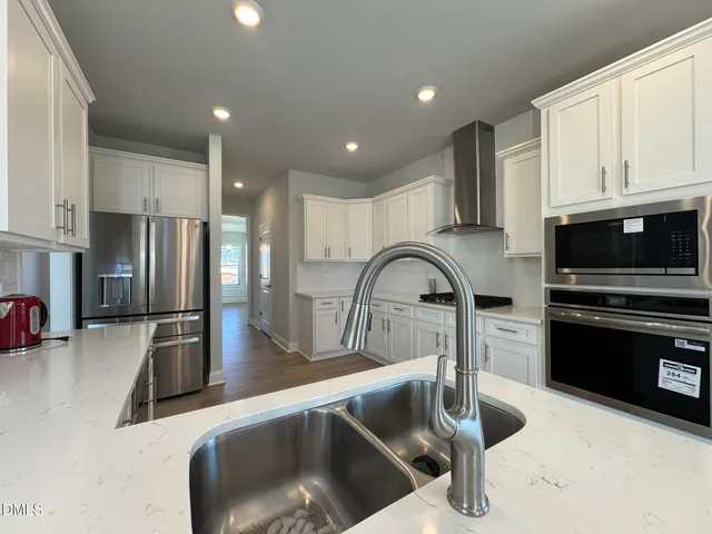 a kitchen with stainless steel appliances granite countertop a sink a stove and a refrigerator with wooden floor