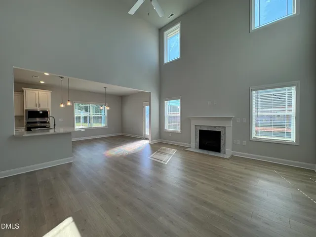an empty room with wooden floor a fireplace and windows