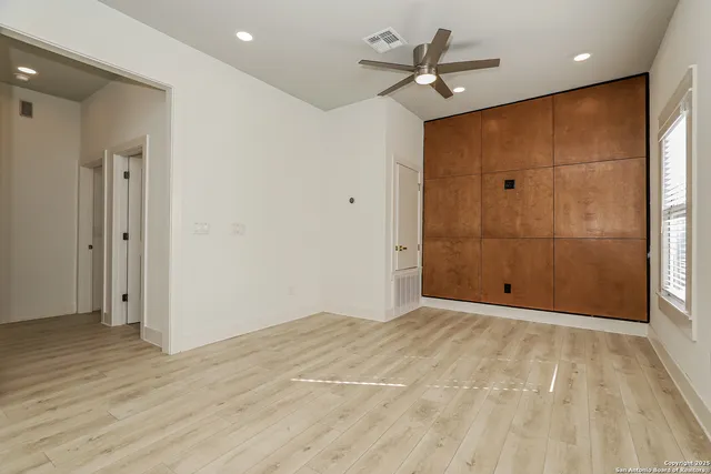an empty room with wooden floor and a ceiling fan