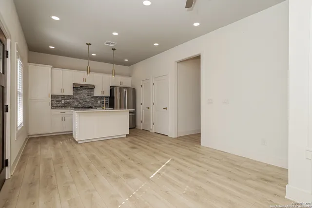 a view of kitchen with kitchen island a sink wooden floor and white appliances