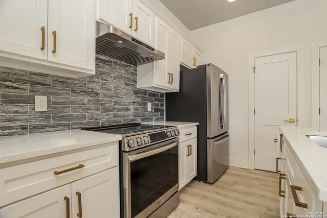 a kitchen with stainless steel appliances wooden floor sink and wooden cabinets