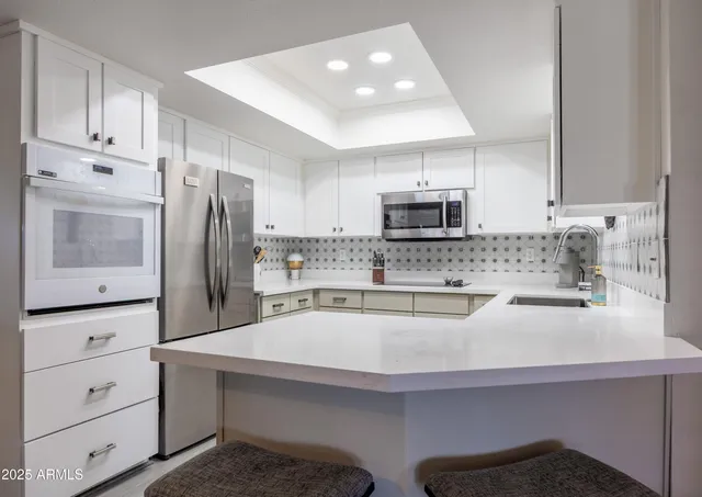 a kitchen with white cabinets and stainless steel appliances