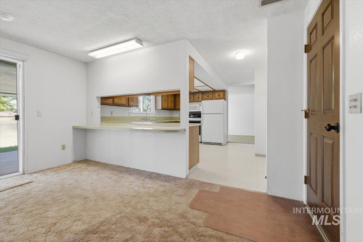 1311 North Middleton Road Nampa, ID 83651 - Photo 43 of 49 Carpeted living area with a breakfast bar, sliding glass door, and overhead lighting