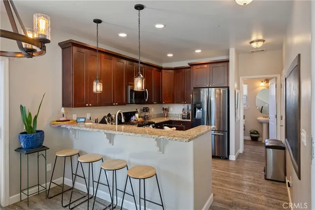 a kitchen with granite countertop a refrigerator a stove a sink and a dining table with wooden floor