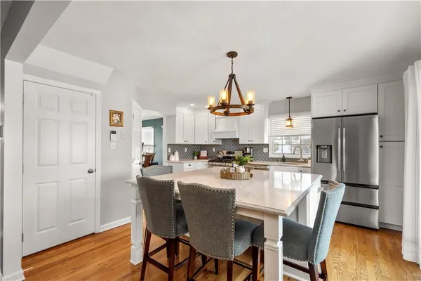 a kitchen with stainless steel appliances a dining table chairs and wooden floor