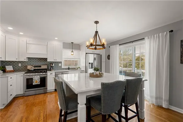 a kitchen with granite countertop a stove a sink dishwasher a dining table and chairs with wooden floor