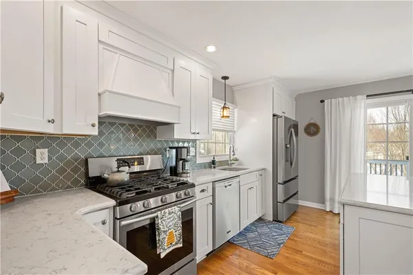 a kitchen with stainless steel appliances granite countertop a stove a refrigerator and a white cabinets