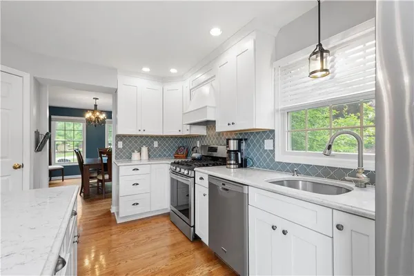 a kitchen with a sink stove cabinets and wooden floor
