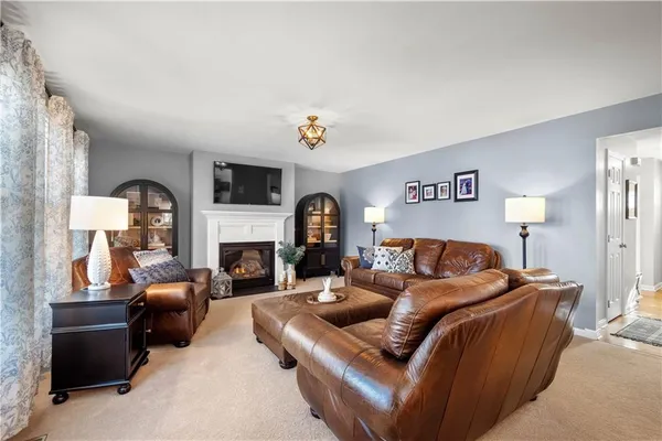 a living room with furniture a fireplace and a large mirror with wooden floor