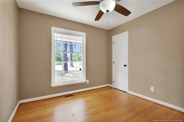 an empty room with windows and fan