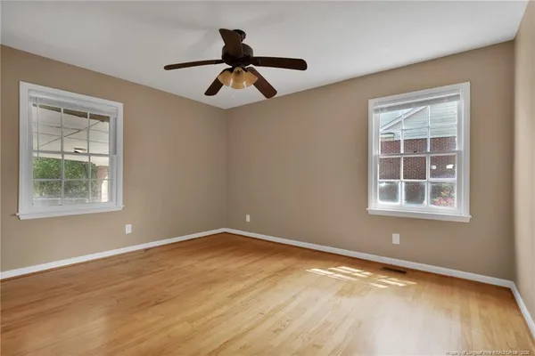 a view of empty room with wooden floor and fan