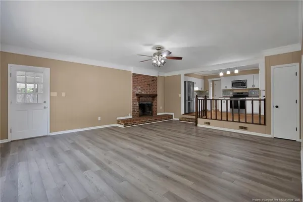 a view of a livingroom with wooden floor a ceiling fan and windows
