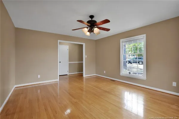 a view of an empty room with window and wooden floor