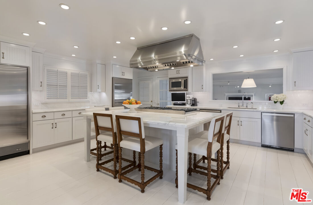 23430 Malibu Colony Road, Unit 95 Malibu, CA 90265 - Photo 17 of 35 a kitchen with stainless steel appliances kitchen island granite countertop a sink a stove a dining table and chairs