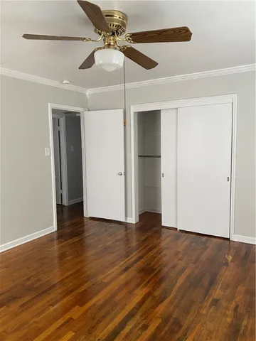 an empty room with wooden floor closet fan and windows