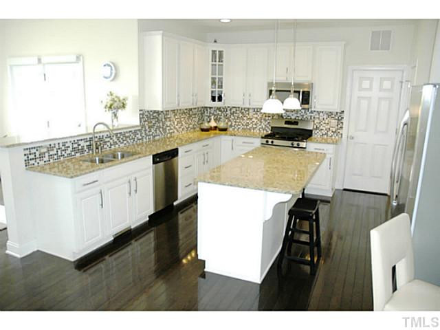 702 Ivyshaw Road Cary, NC 27519 - Photo 6 of 25 White cabinets, granite, SS appliances with dark hardwoods.....cooking in style! Center island great for quick snacks and food prep! Kitchen
