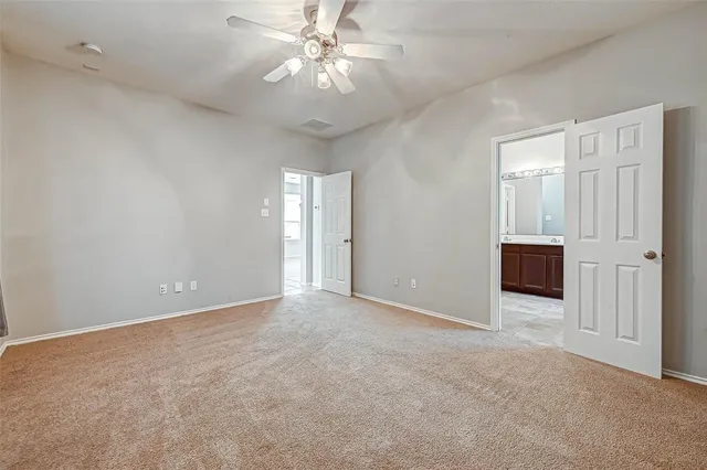 an empty room with chandelier fan and windows